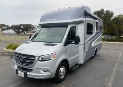Silver Tiffin motorhome/RV with Mercedes chassis parked in lot, compact Class C recreational vehicle.