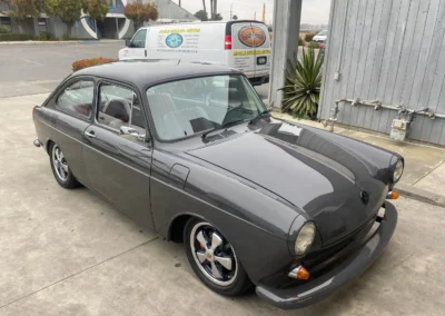 A vintage grey Volkswagen Type 3 Fastback in pristine condition, parked outdoors.